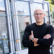 Chef der Firma Hefa Fenster Türen Markisen vor Fenstern stehend.