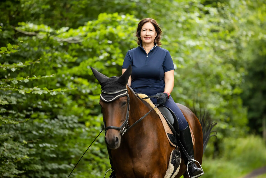 Personal Branding Fotos für die Über-Mich-Seite von Karina Schuh, authentisches Portrait von Nieke Arendt von PersonalCheck während ihrer Freizeitbeschäftigung, dem Reiten. Zu sehen ist sie sitzend auf ihrem Pferd im Wald.