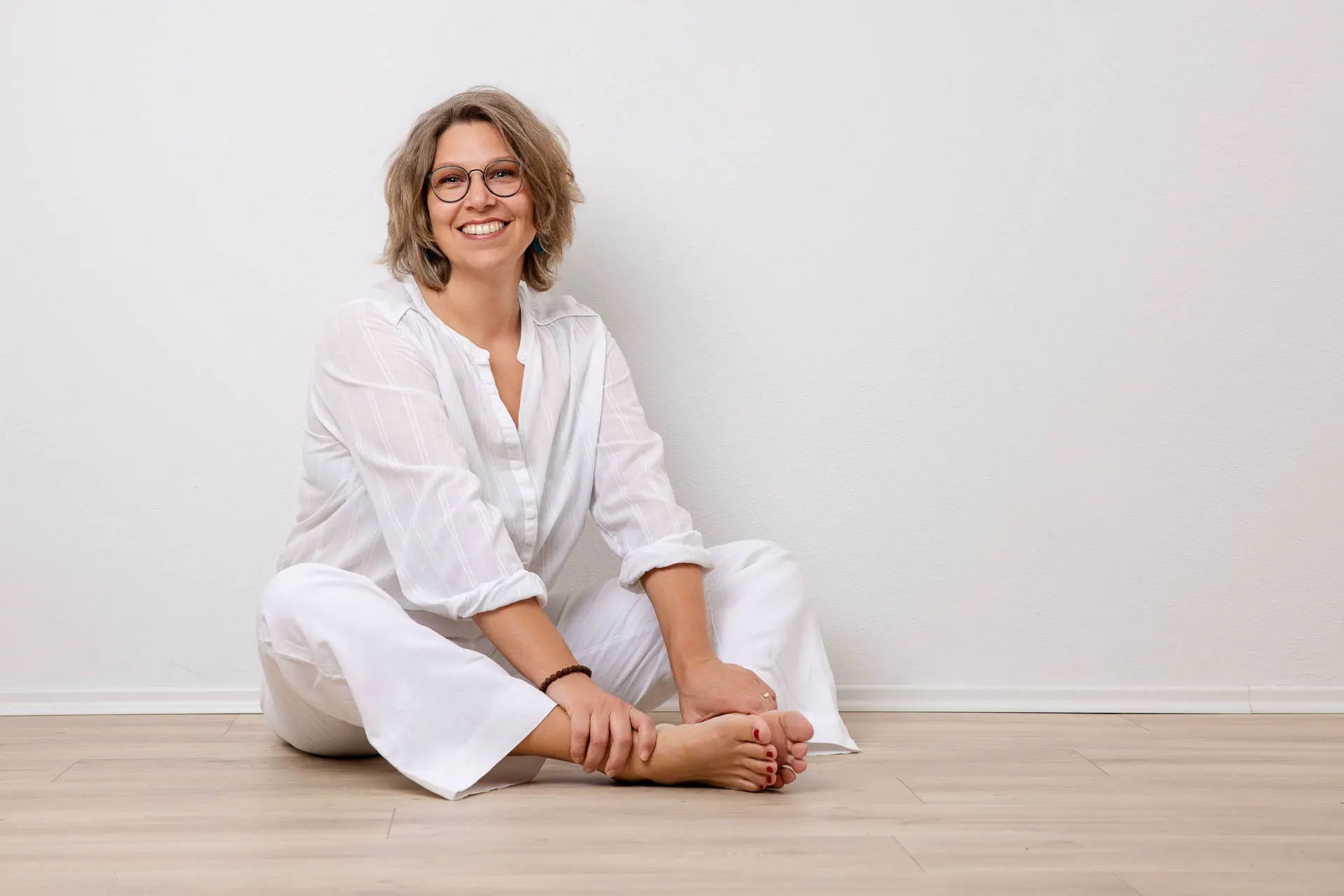 Minimalismus im Fotoshooting - Minimalistisches Portrait einer Frau in weißem Oberteil vor einem hellen Hintergrund. Schlichter Stil, der den Fokus auf die Persönlichkeit lenkt.