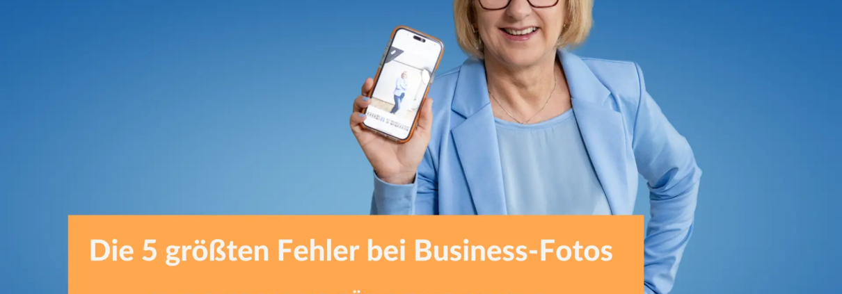 Fotografin in einem hellblauen Blazer lächelt und hält ein Smartphone mit einem Business-Foto in die Kamera, vor einem blauen Hintergrund. Textoverlay: „Die 5 größten Fehler bei Business-Fotos und wie du sie für deine Online-Sichtbarkeit vermeidest“.