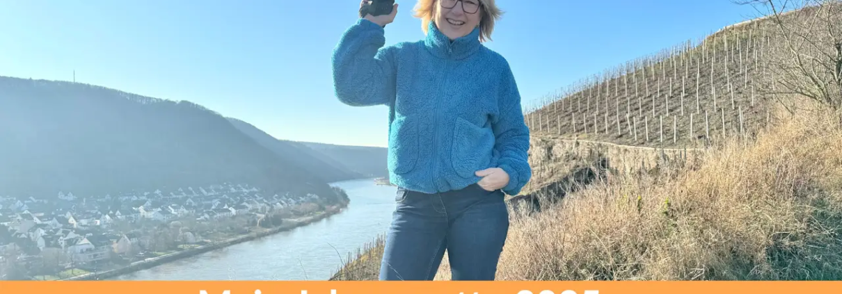 Karina Schuh, Fotografin, in einer entspannten Pose mit Kamera in der Hand, lächelnd vor einer malerischen Landschaft hoch über der Mosel. Text: Mein Jahresmotto 2025 – Leichtigkeit.