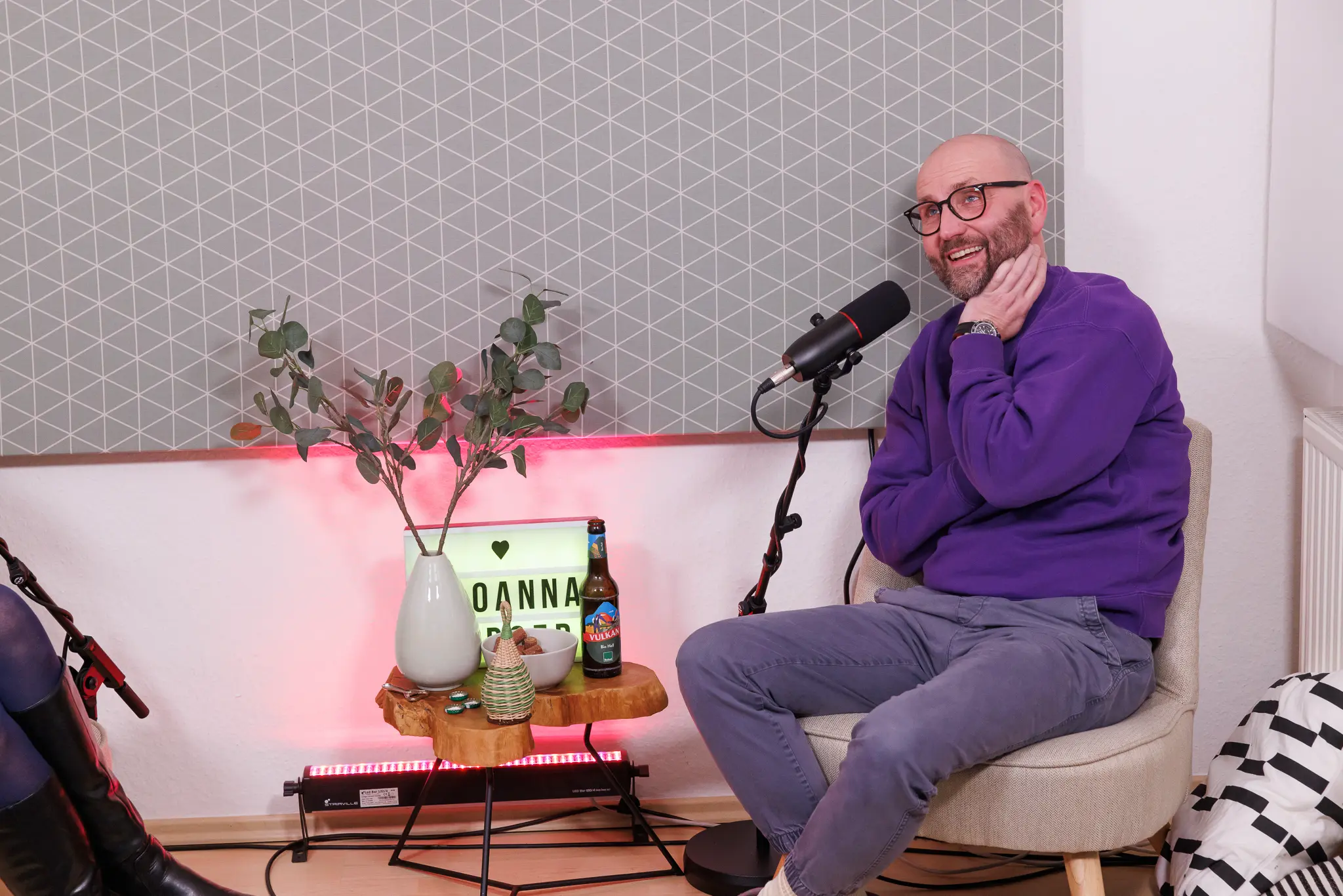 Christian Schmidt lächelt entspannt, während er im Tiny Studio Talk über ein Thema spricht. Auf dem Tisch neben ihm stehen Dekorationen und eine Flasche B