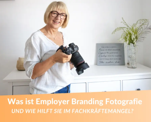 Was ist Employer Branding Fotografie? Fotografin für Unternehmensfotos mit blonden Haaren. Sie schaut in die Kamera und hält selbst eine Kamera in der Hand!