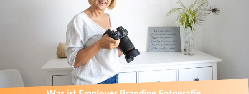 Was ist Employer Branding Fotografie? Fotografin für Unternehmensfotos mit blonden Haaren. Sie schaut in die Kamera und hält selbst eine Kamera in der Hand!