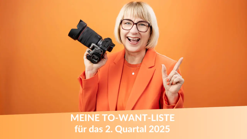 Karina Schuh trägt ein orangefarbenes Outfit, lächelt in die Kamera und hält ihre Kamera in der Hand. Der Hintergrund ist orange. Darunter steht in Weiß: "MEINE TO-WANT-LISTE für das 2. Quartal 2025"