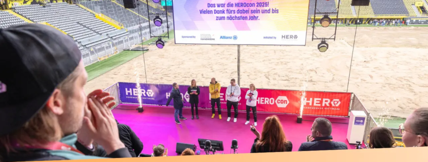 HEROCON 2025 Abschluss auf der HERO Stage mit Team vor LED-Leinwand im Signal Iduna Park.
