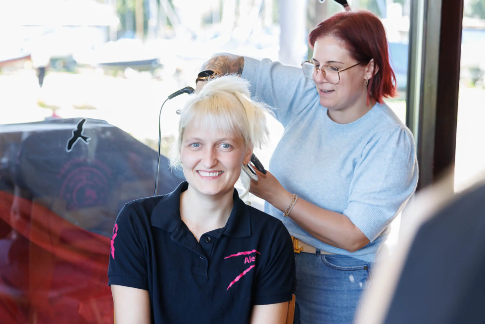 Friseurmeisterin Sabrina Heilig vom Salon HairDaun stylt die Haare einer lachenden Pink Paddlerin beim Fotoshooting in Koblenz.